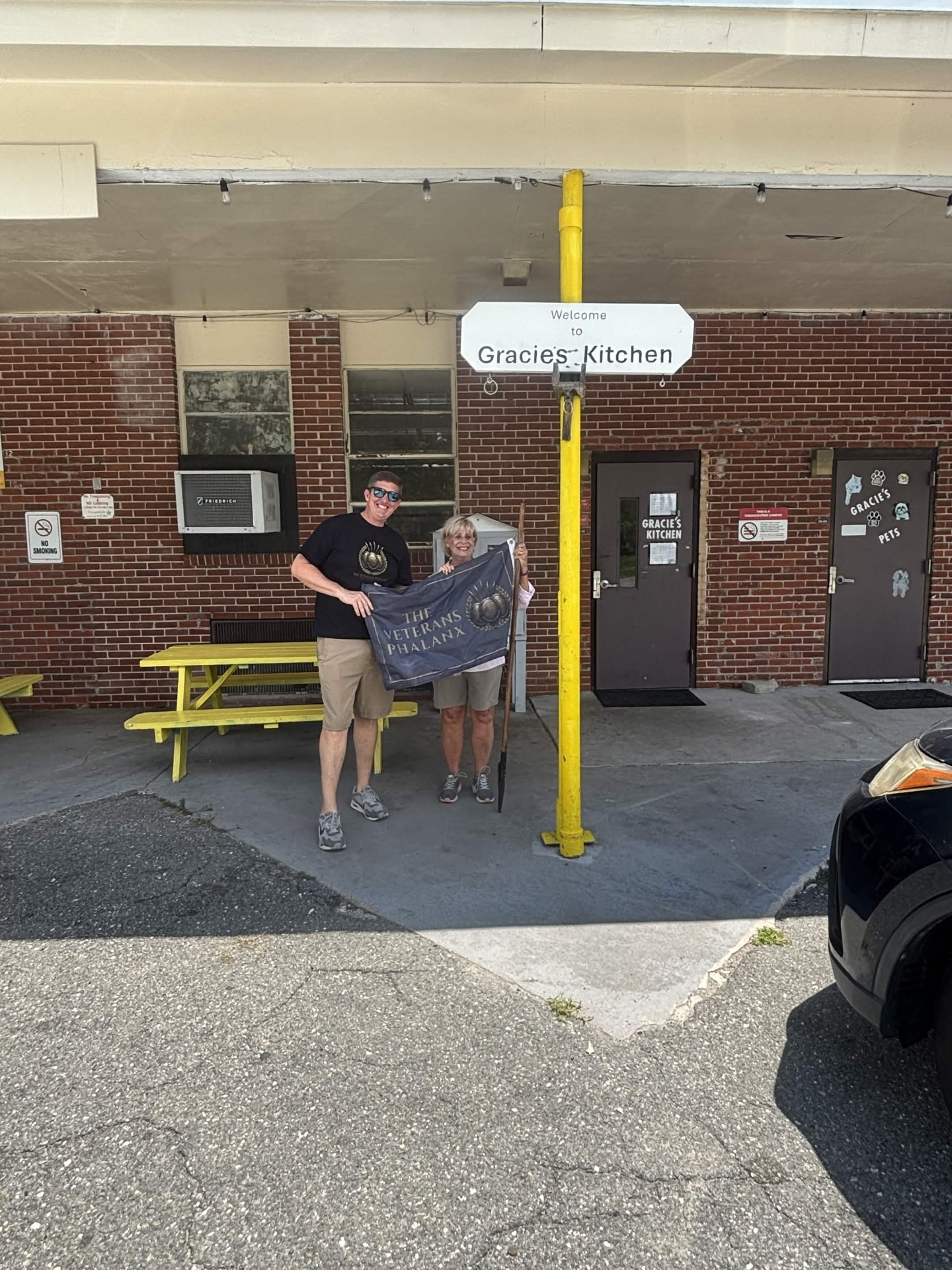 Eric Jones and Ms. Maryellen Crocker holding The Veterans Phalanx Standard outside Gracie's Kitchen.