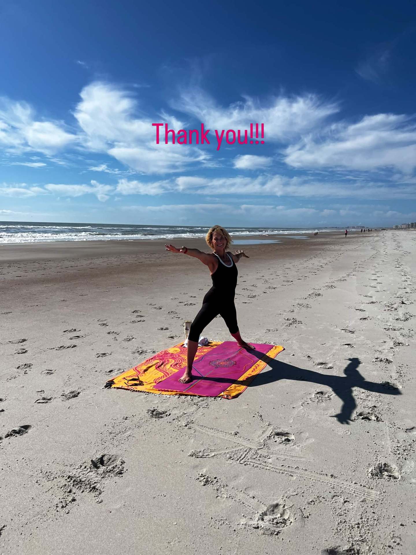 A yoga instructor in warrior pose on a mat at the beach during United on The Sand.